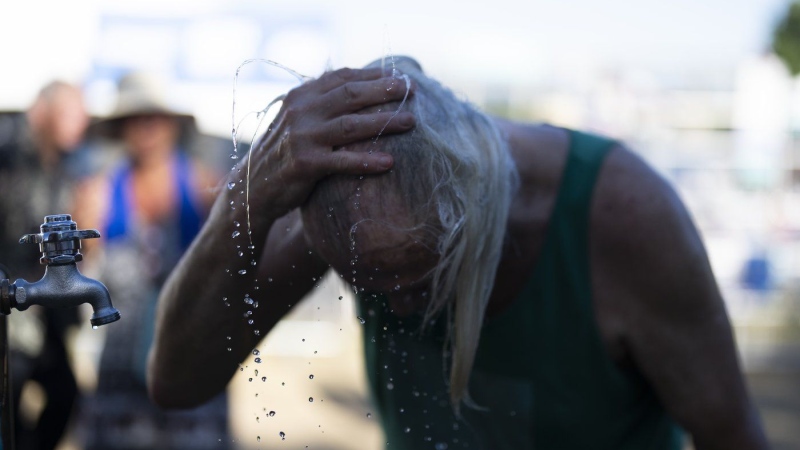 A person cools off during the Waterfront Blues Festival on Friday, July 5, 2024, in Portland, Ore. A slow-moving and potentially record-setting heat wave is spreading across the Western U.S., sending many residents in search of a cool haven from the dangerously high temperatures. (AP Photo/Jenny Kane)